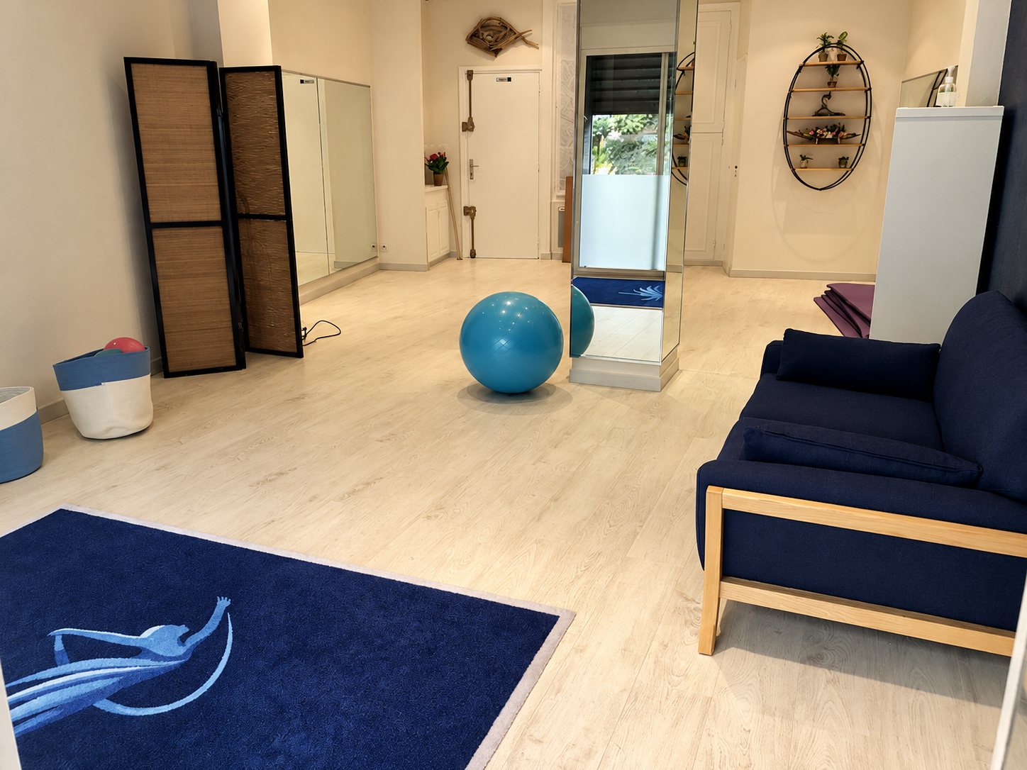 Salle lumineuse avec ballon bleu, miroirs et canapé bleu marine